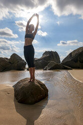 Seychellen, Mahe, Takamaka Beach, Frau macht Yoga auf einem Felsen - NDF00916