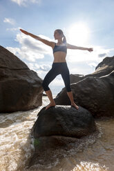 Seychelles, Mahe, Takamaka Beach, mature woman doing yoga on a rock - NDF00920