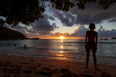 Seychellen, Mahe, Takamaka Beach, Silhouette eines am Strand stehenden Mannes bei Sonnenuntergang - NDF00922