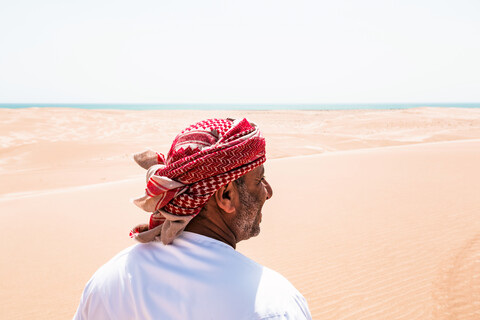 Beduine in Nationaltracht in der Wüste stehend, Rückansicht, Wahiba Sands, Oman, lizenzfreies Stockfoto