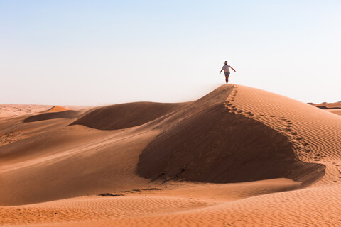 Mann geht auf einer Sanddüne, Wahiba Sands, Oman, lizenzfreies Stockfoto