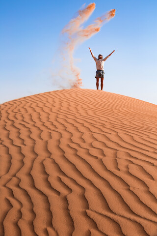 Sultanate Of Oman, Wahiba Sands, Mid adult man is playing with sand in the desert stock photo