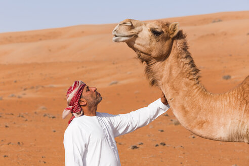 Beduine streichelt sein Kamel in der Wüste, Wahiba Sands, Oman - WVF01362