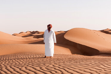 Beduine in Nationaltracht in der Wüste stehend, Rückansicht, Wahiba Sands, Oman - WVF01383