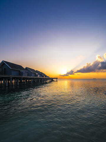 Malediven, Ross Atoll, Wasserbungalows bei Sonnenuntergang, lizenzfreies Stockfoto