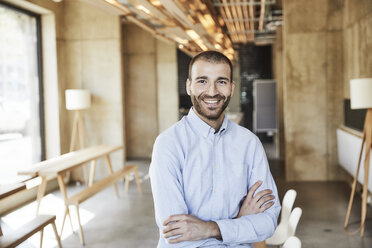 Portrait of smiling businessman in modern office - FMKF05547