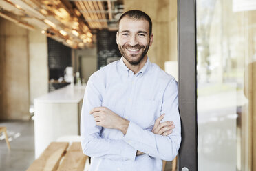 Portrait of smiling businessman in modern office - FMKF05548