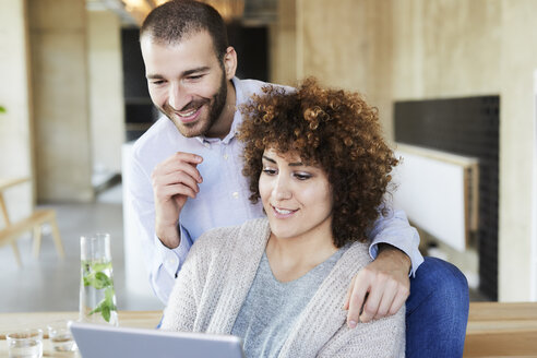 Glücklicher Mann und Frau teilen sich ein Tablet in einem modernen Büro - FMKF05554