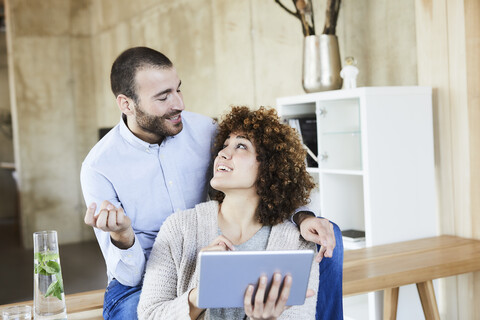 Glücklicher Mann und Frau mit Tablet im Gespräch im modernen Büro, lizenzfreies Stockfoto