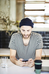Young man wearing a beanie using cell phone - FMKF05568