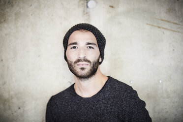 Portrait of confident young man at concrete wall - FMKF05571