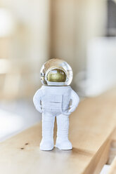 Miniature astronaut figurine on wooden bench - FMKF05582