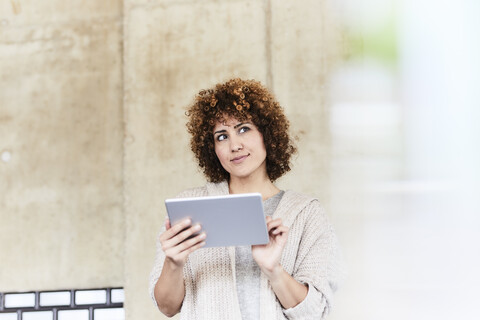 Smiling woman using tablet at concrete wall stock photo