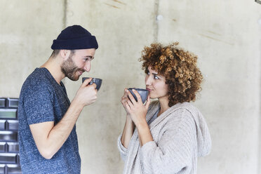 Mann und Frau trinken Kaffee und lächeln sich gegenseitig an - FMKF05604