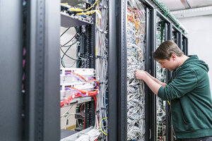 Teenager bei der Arbeit mit Kabeln im Serverraum - DIGF06730