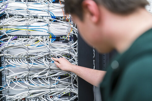 Nahaufnahme eines Teenagers bei der Arbeit mit Kabeln im Serverraum - DIGF06732