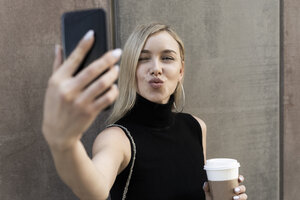 Porträt einer blonden Frau mit Kaffee zum Mitnehmen, die ein Selfie mit ihrem Smartphone macht - GIOF06228