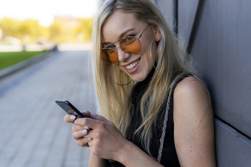 Porträt einer lächelnden jungen Frau mit Smartphone - GIOF06251