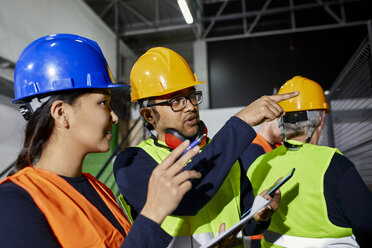 Mann im Gespräch mit einer Arbeiterin in einer Fabrikhalle - ZEDF02080