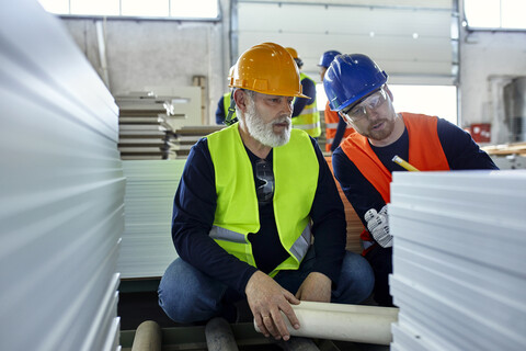 Zwei Männer arbeiten zusammen in einer Fabrik, lizenzfreies Stockfoto