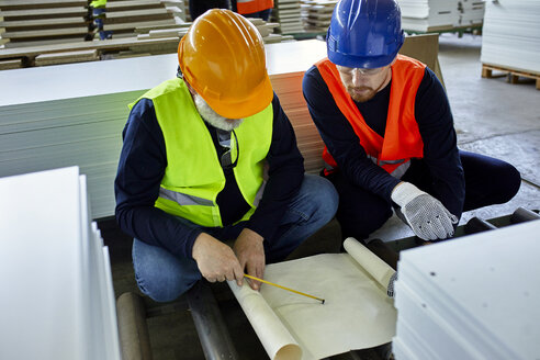 Zwei Männer arbeiten an einem Plan in einer Fabrik - ZEDF02083