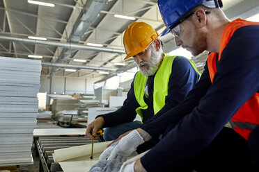 Zwei Männer arbeiten an einem Plan in einer Fabrik - ZEDF02084