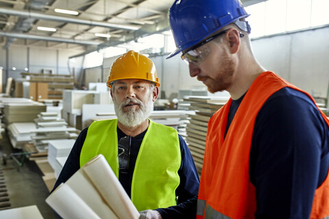 Zwei Männer arbeiten an einem Plan in einer Fabrik, lizenzfreies Stockfoto