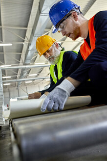 Zwei Männer arbeiten an einem Plan in einer Fabrik - ZEDF02086