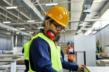 Worker examining wooden board in factory - ZEDF02097