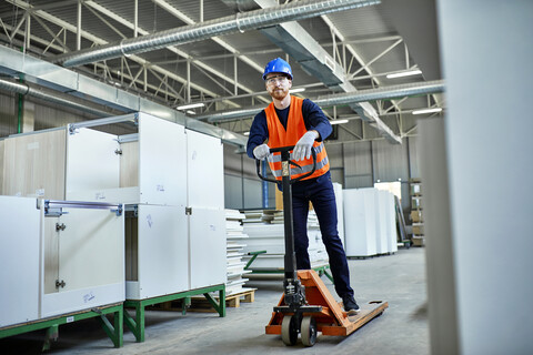 Arbeiter, der in einer Fabrik auf einem Hubwagen fährt, lizenzfreies Stockfoto