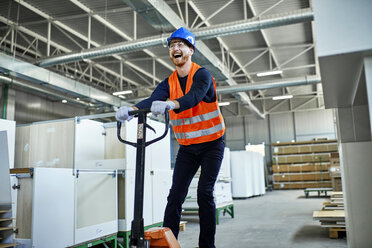 Lachender Arbeiter auf einem Palettenheber in einer Fabrik - ZEDF02117