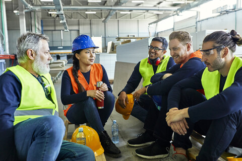 Arbeiter in einer Fabrik machen gemeinsam Mittagspause, lizenzfreies Stockfoto