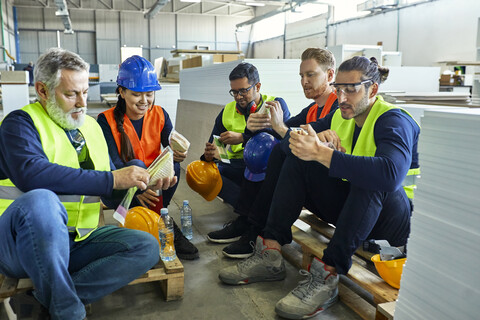 Arbeiter in einer Fabrik machen gemeinsam Mittagspause, lizenzfreies Stockfoto