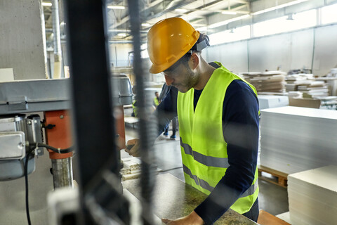 Arbeiter, der eine Bohrmaschine in einer Fabrik bedient, lizenzfreies Stockfoto