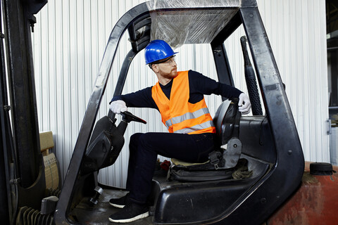 Arbeiter auf einem Gabelstapler in einer Fabrik beim Umdrehen, lizenzfreies Stockfoto