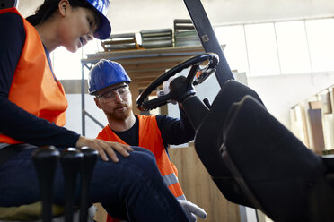 Mann instruiert Arbeiterin auf Gabelstapler in Fabrik - ZEDF02153