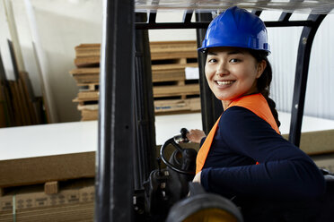 Porträt einer selbstbewussten Arbeiterin auf einem Gabelstapler in einer Fabrik - ZEDF02157