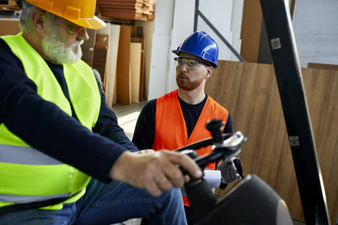 Mann spricht mit Arbeiter auf Gabelstapler in Fabrik - ZEDF02163