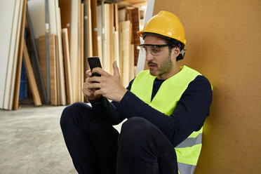 Arbeiter, der während einer Pause in der Fabrik ein Mobiltelefon benutzt - ZEDF02167