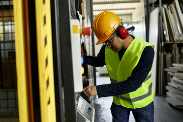 Mann, der eine Maschine in einer industriellen Fabrik bedient - ZEDF02169