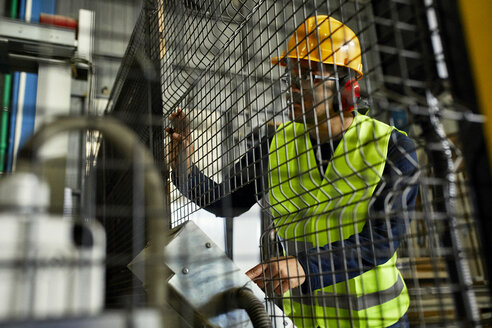 Mann, der eine Maschine in einer industriellen Fabrik bedient - ZEDF02171