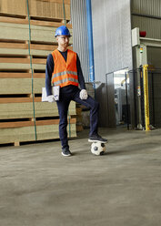 Worker standing in factory warehouse with football - ZEDF02172