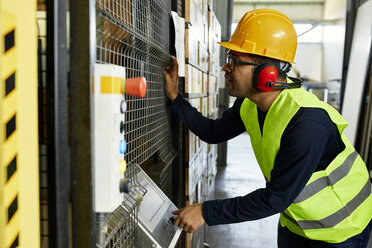 Mann, der eine Maschine in einer industriellen Fabrik bedient - ZEDF02173