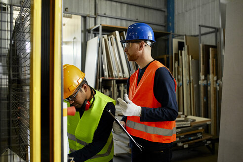 Zwei Männer bedienen eine Maschine in einer industriellen Fabrik - ZEDF02175