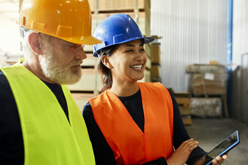 Männlicher und weiblicher Arbeiter mit Tablet arbeiten zusammen in einer Fabrik - ZEDF02177