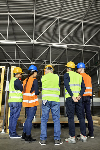 Rückansicht von Arbeitern, die in einer Fabrikhalle stehen, lizenzfreies Stockfoto