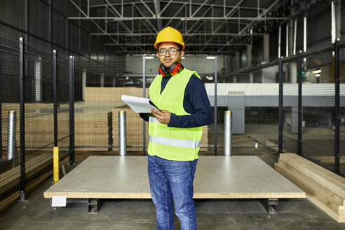 Porträt eines Arbeiters mit Zwischenablage in einem Fabriklager - ZEDF02195