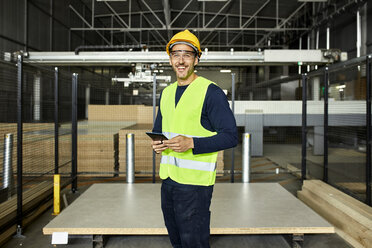 Porträt eines lächelnden Arbeiters mit Tablet in einem Fabriklager - ZEDF02201