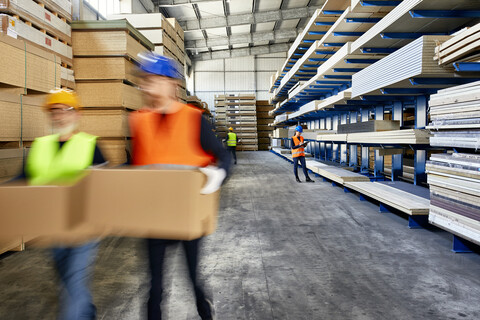 Workers moving and carrying boxes in factory warehouse stock photo