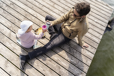 Germany, Bavaria, Herrsching, father and daughter relaxing on jetty having a snack - DIGF06737